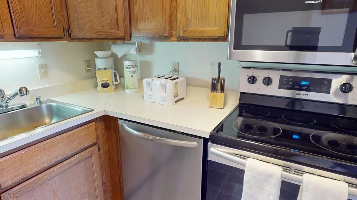 A cozy kitchen area with visible appliances, a spacious countertop for meal prep, and warm wooden cabinets. The overall vibe is functional yet welcoming, ideal for both cooking and casual conversations.