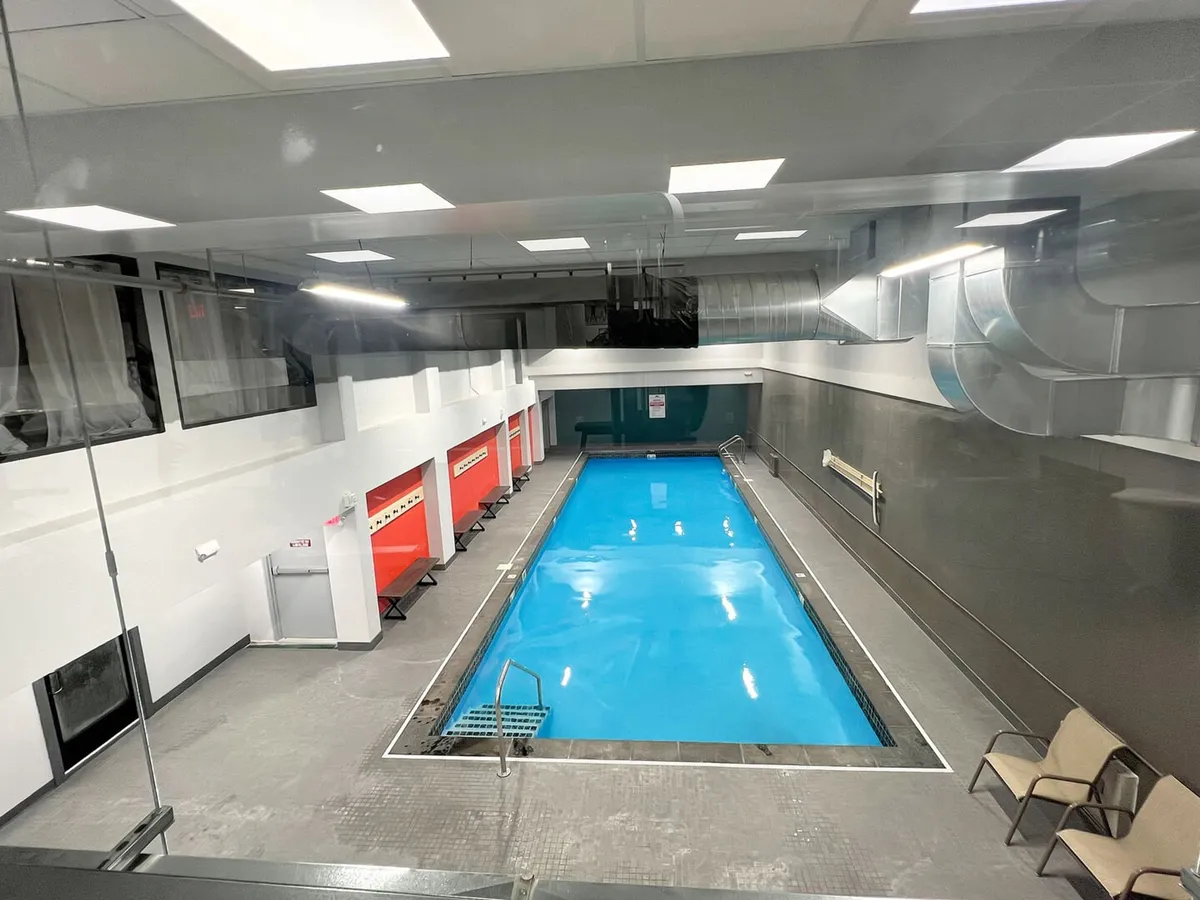 A bright indoor swimming pool area featuring red changing rooms and a comfortable seating area. The pool offers opportunities for both fitness and relaxation in a warm, inviting environment, even during the cold winter months.