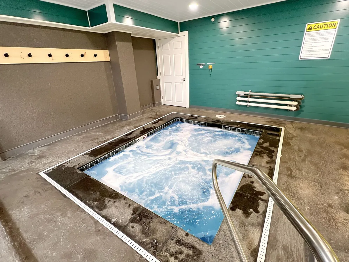 A serene hot tub area with warm lighting and a calm ambiance, inviting guests to relax and unwind after an active day on the slopes. The hot tub is the focal point, with signage and decor emphasizing relaxation and self-care.