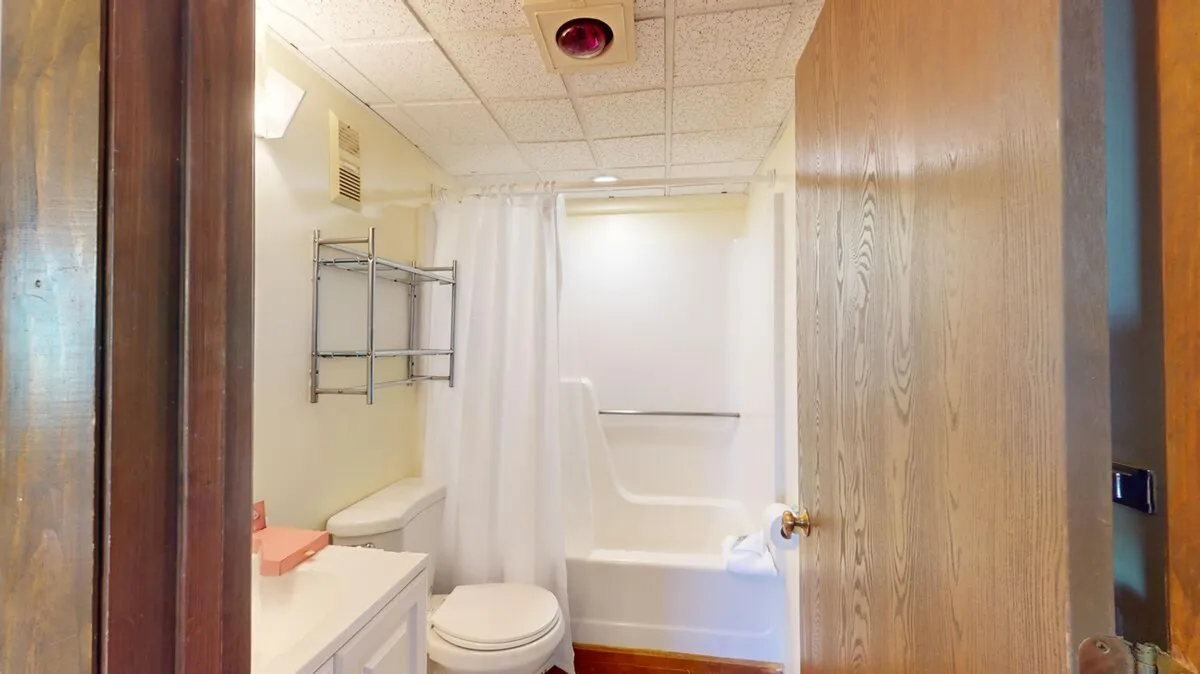 A well-lit bathroom featuring a practical vanity with sink, a toilet, and a glass-enclosed shower area. The neutral color palette and simple design emphasize comfort and functionality for freshening up after a day outdoors.