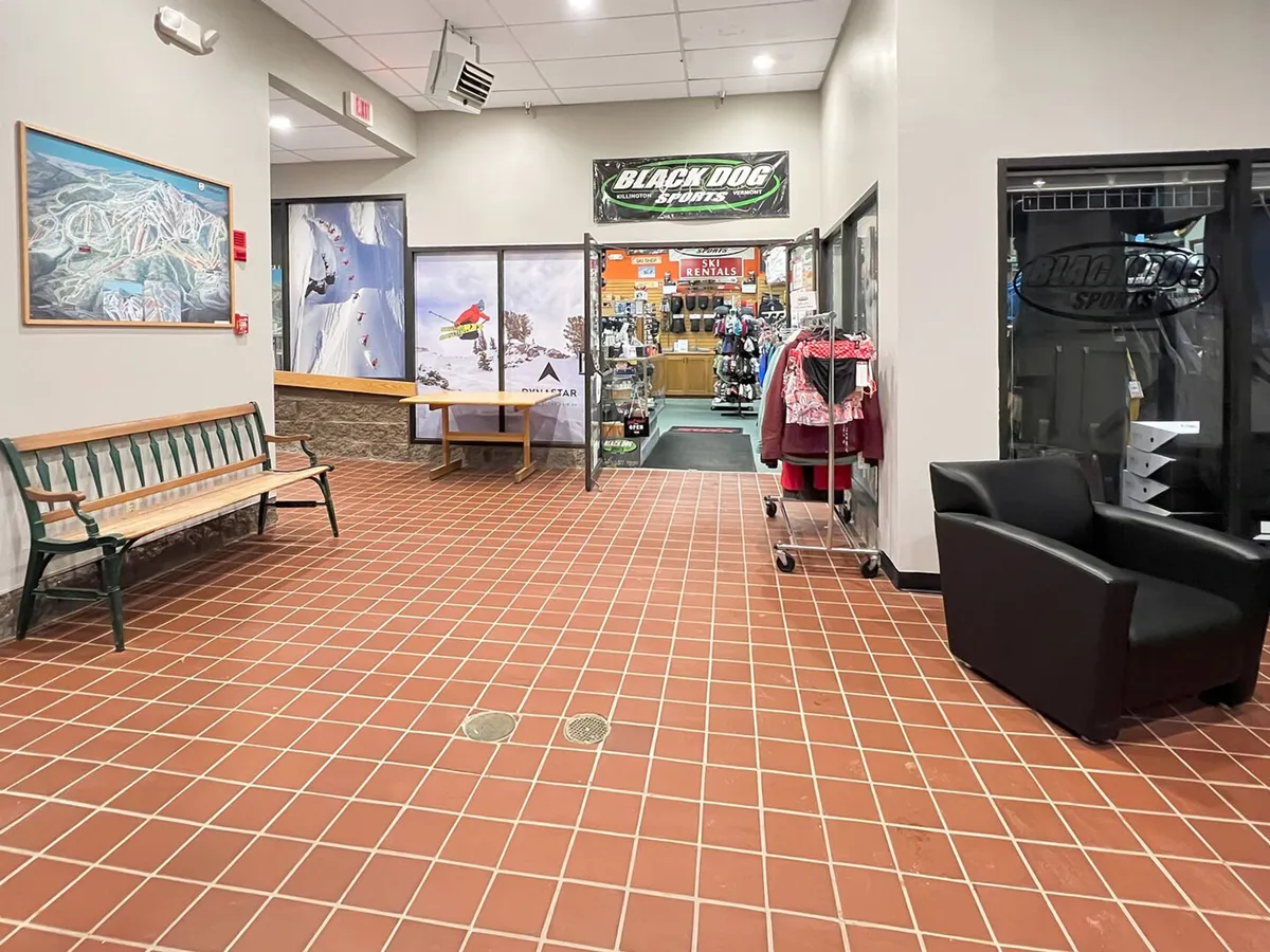 A welcoming interior view of the entrance to Black Dog Sports shop, with displays of sports apparel and a casual seating area. The space is well-lit and active, suggesting convenience and community.